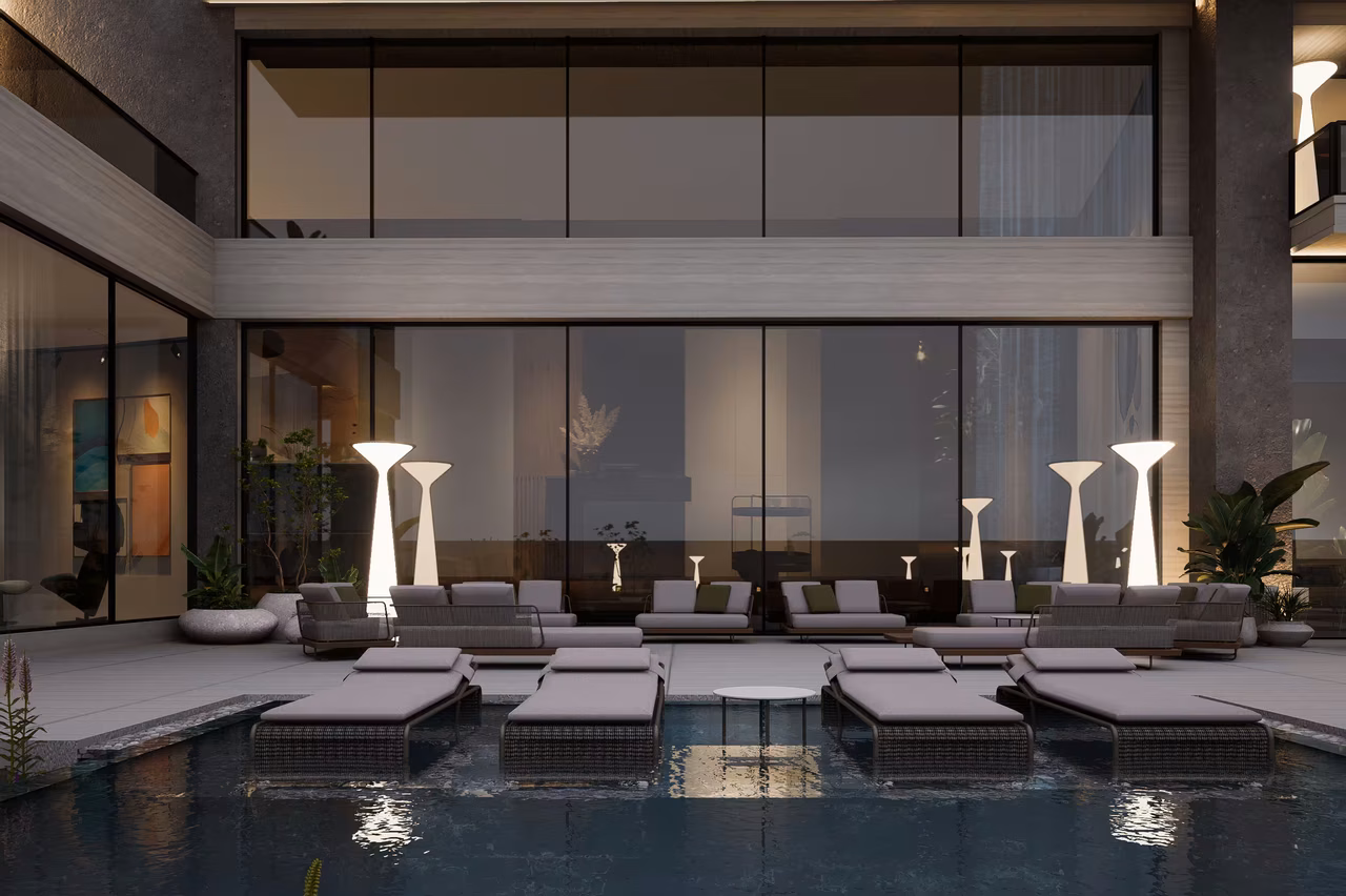 Poolside lounge seating with glass facade and warm exterior lighting